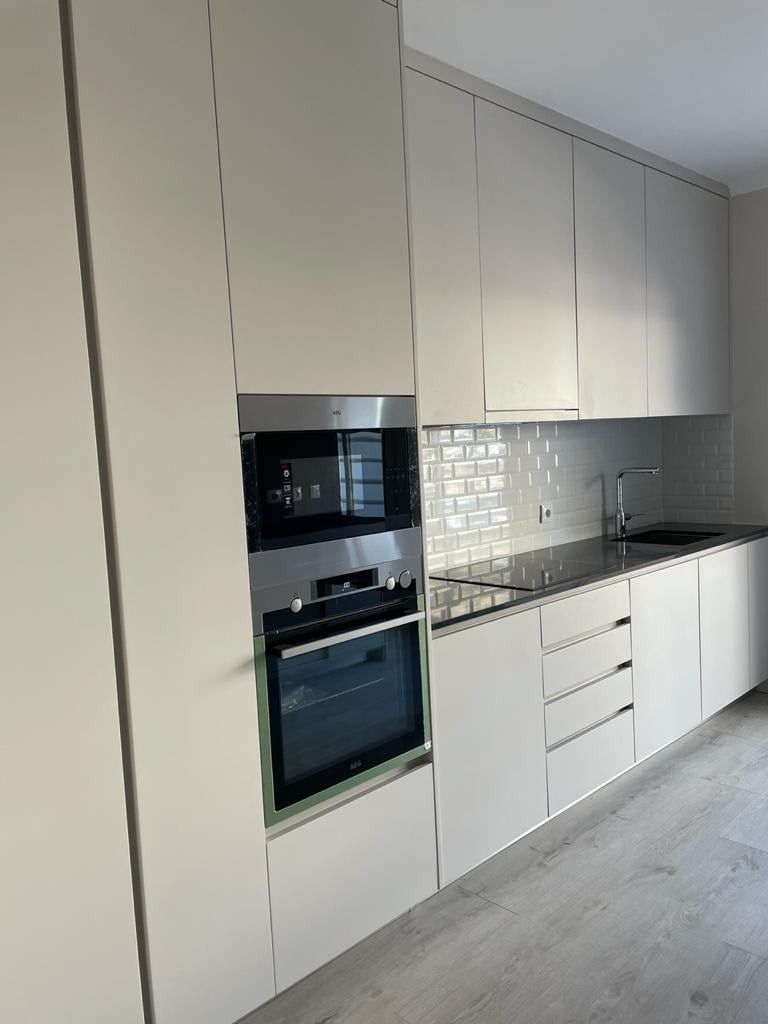 Linéaire de cuisine clair, colonne four et micro-ondes, plan de travail noir et meubles hauts jusqu'au plafond