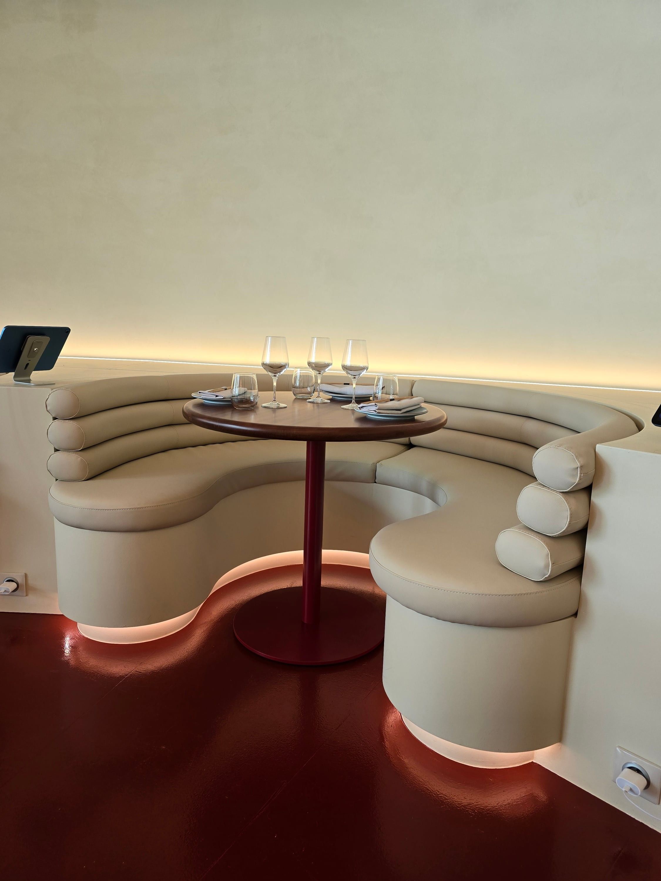 Banquette en alcôve aux formes arrondies, éclairée en pied, autour d'une table ronde